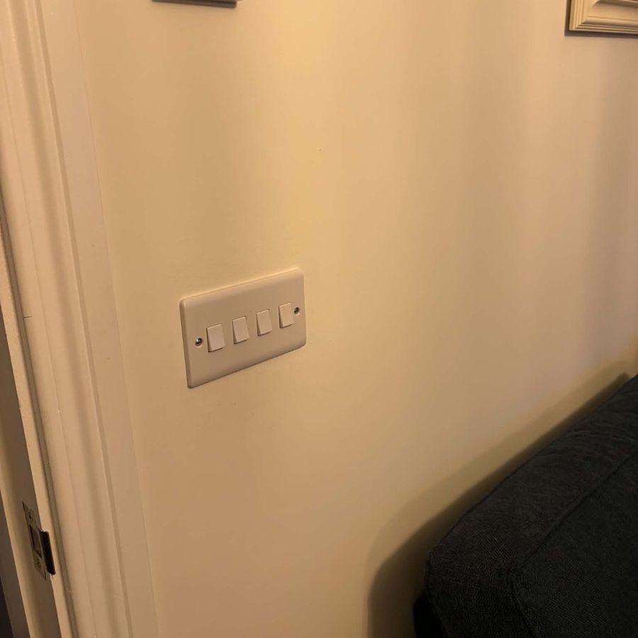 An old four-gang white rocker switch plate on a hallway wall