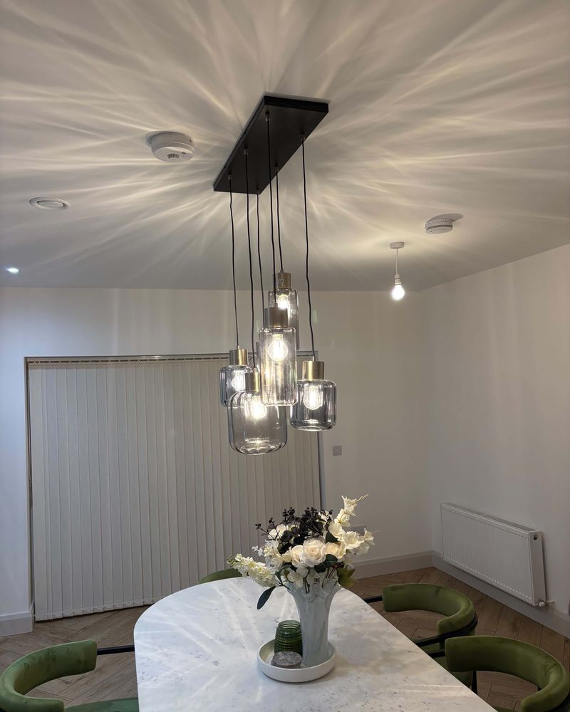A five-shade glass cluster pendant lit above a marble dining table